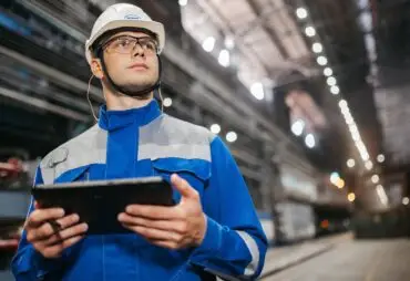 Decorative image for blog post on the importance of cybersecurity for manufacturers and warehouses in Chicagoland. Image depicts man with an ipad in a large warehouse in work clothes.